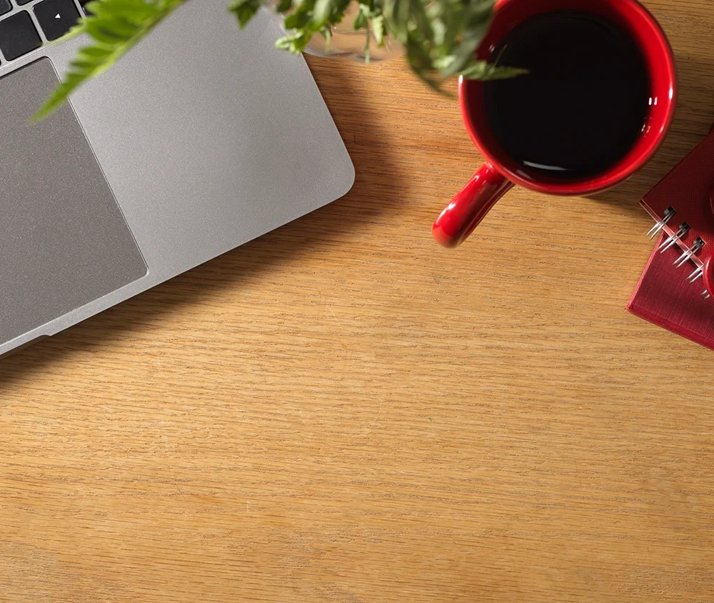 Tasse rouge, plante et ordinateur sur bureau en bois – ambiance de travail créatif