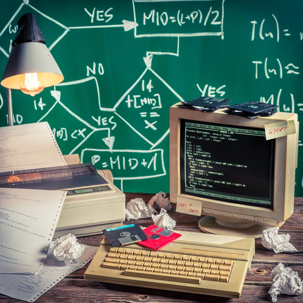 Maikkom agence communication - Poste de développement informatique vintage avec ordinateur rétro, code de programmation et diagramme de flux